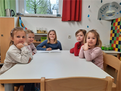 eine Gruppe von Kindern, die an einem Tisch sitzen